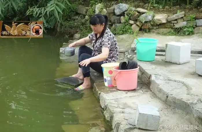 农家大妈在堰塘洗衣服,左手戴着金戒指和金手镯.