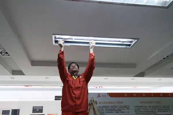 安得维修队人员为彩虹社区办公处安装新灯管